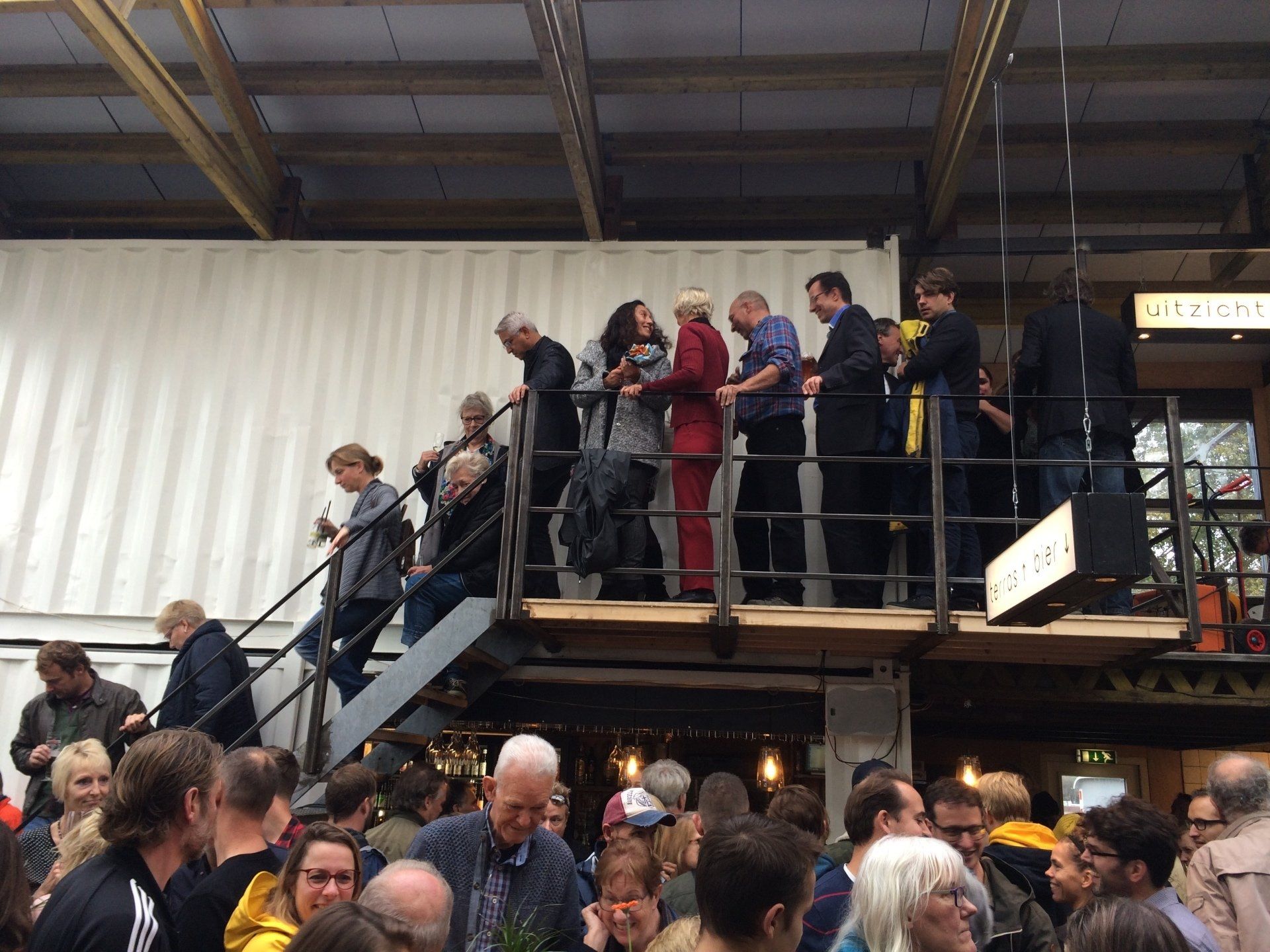 Mensen op een metalen platform met uitzicht op een drukke plek.