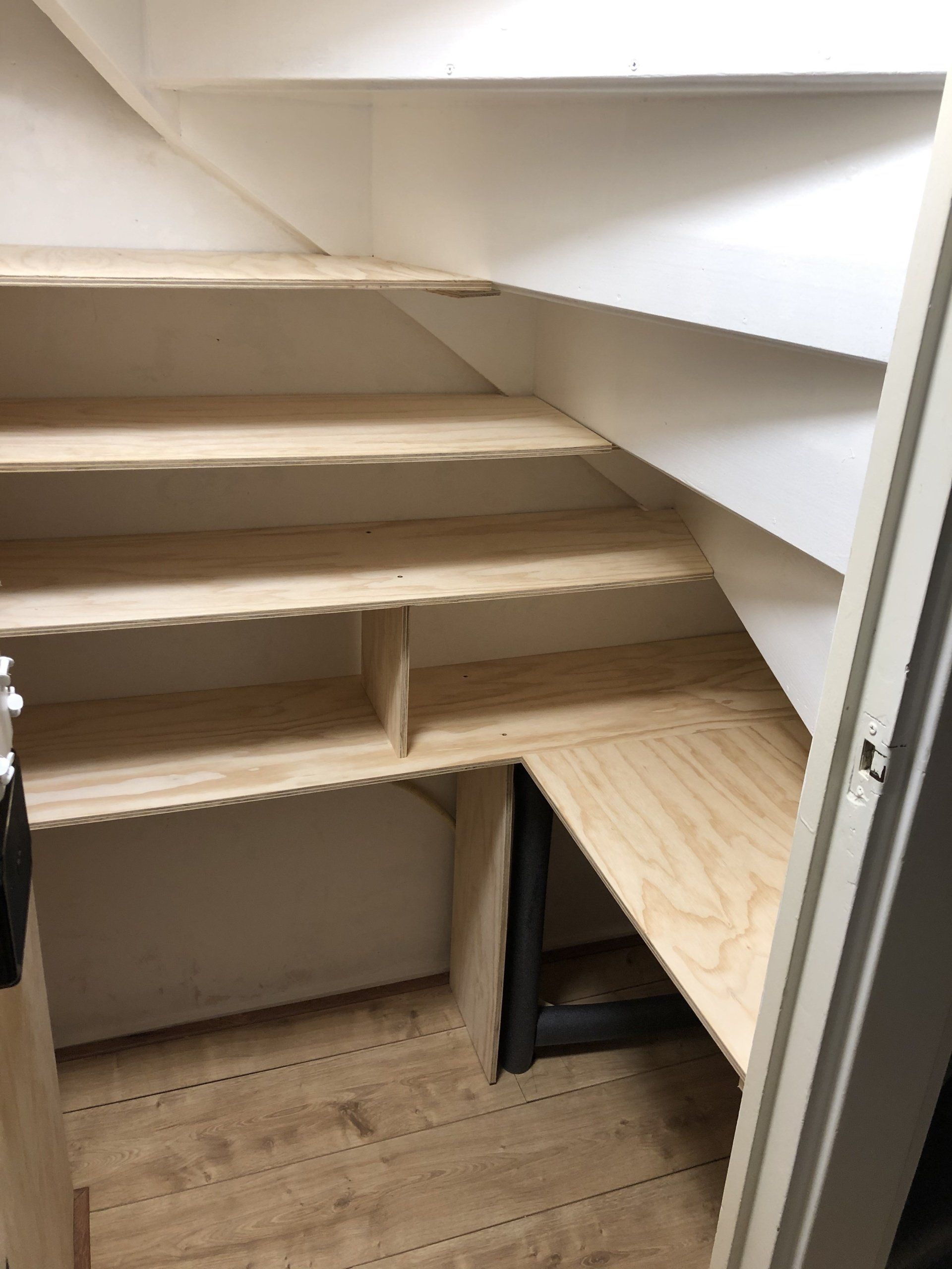 Opbergruimte onder de trap: houten traptreden en planken, ingebouwde opbergruimte onder de trap.