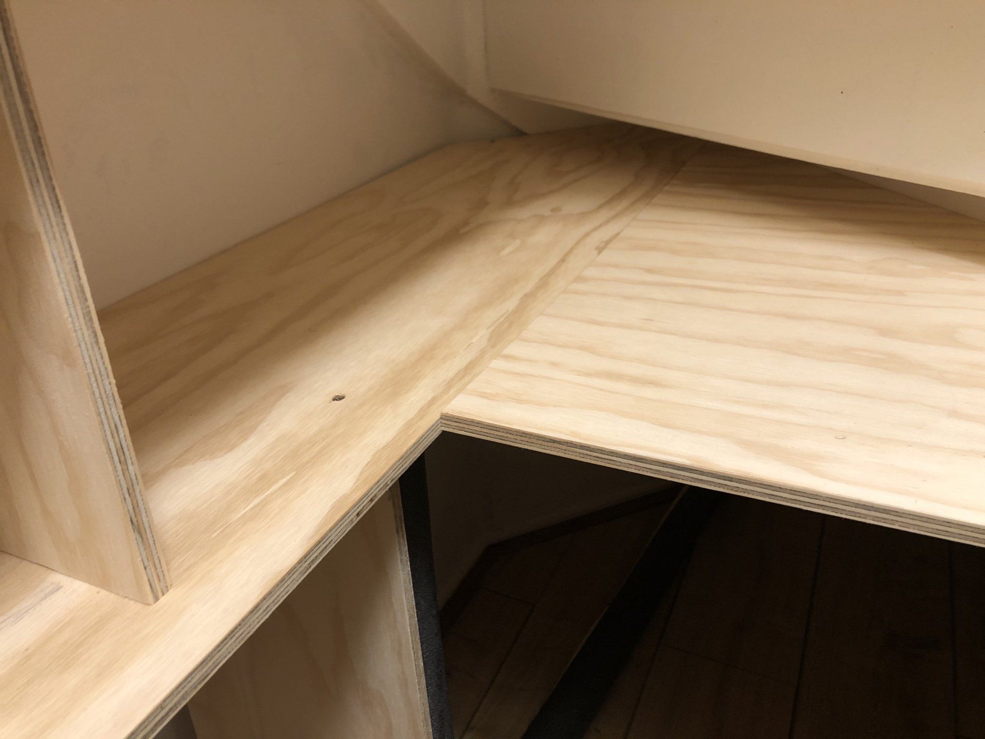 Houten wandrek van lichtgekleurd multiplex. Eén plank bevindt zich onder een schuin plafond.