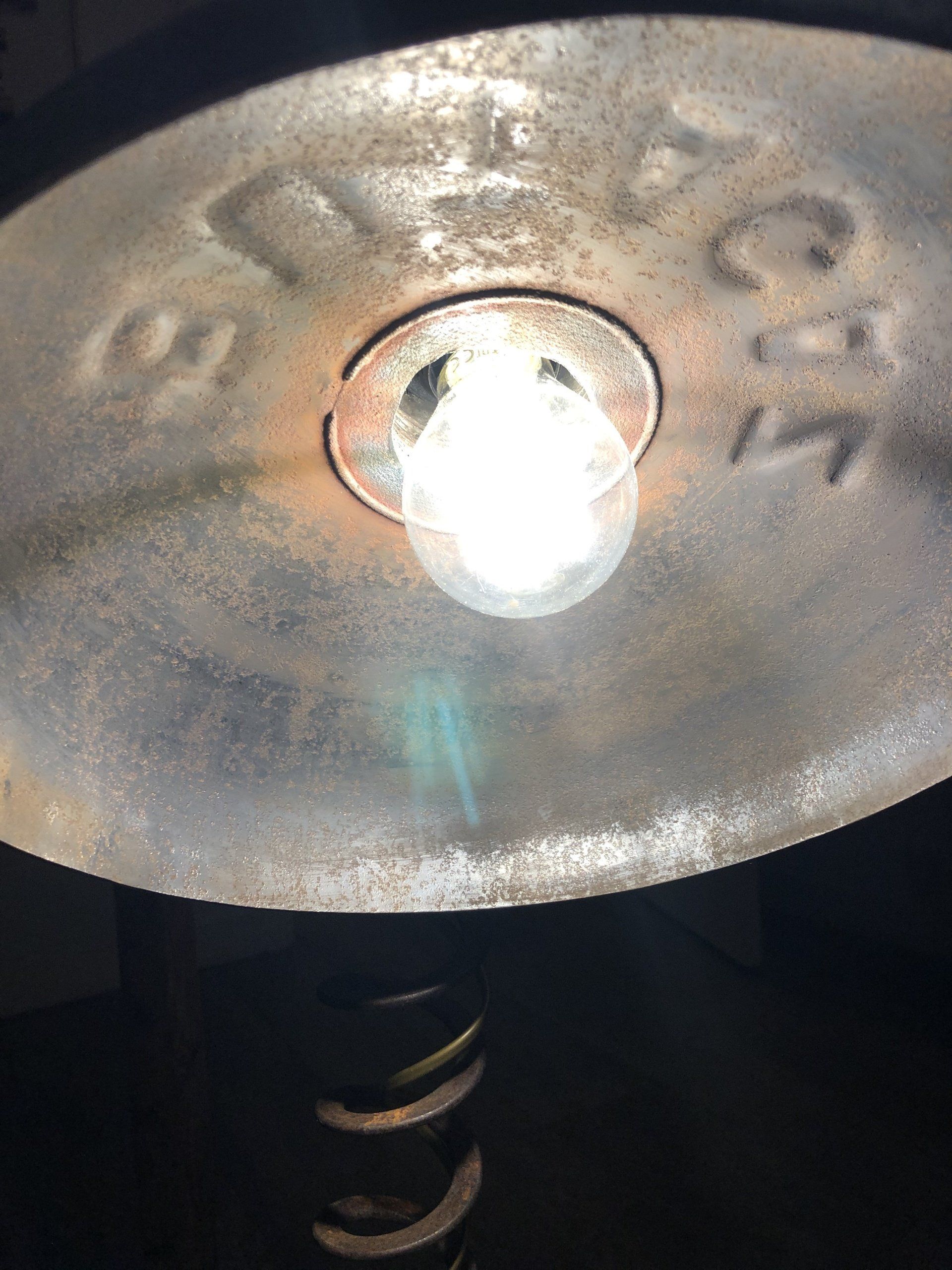 Close-up van een brandende gloeilamp in een roestige metalen lampenkap.