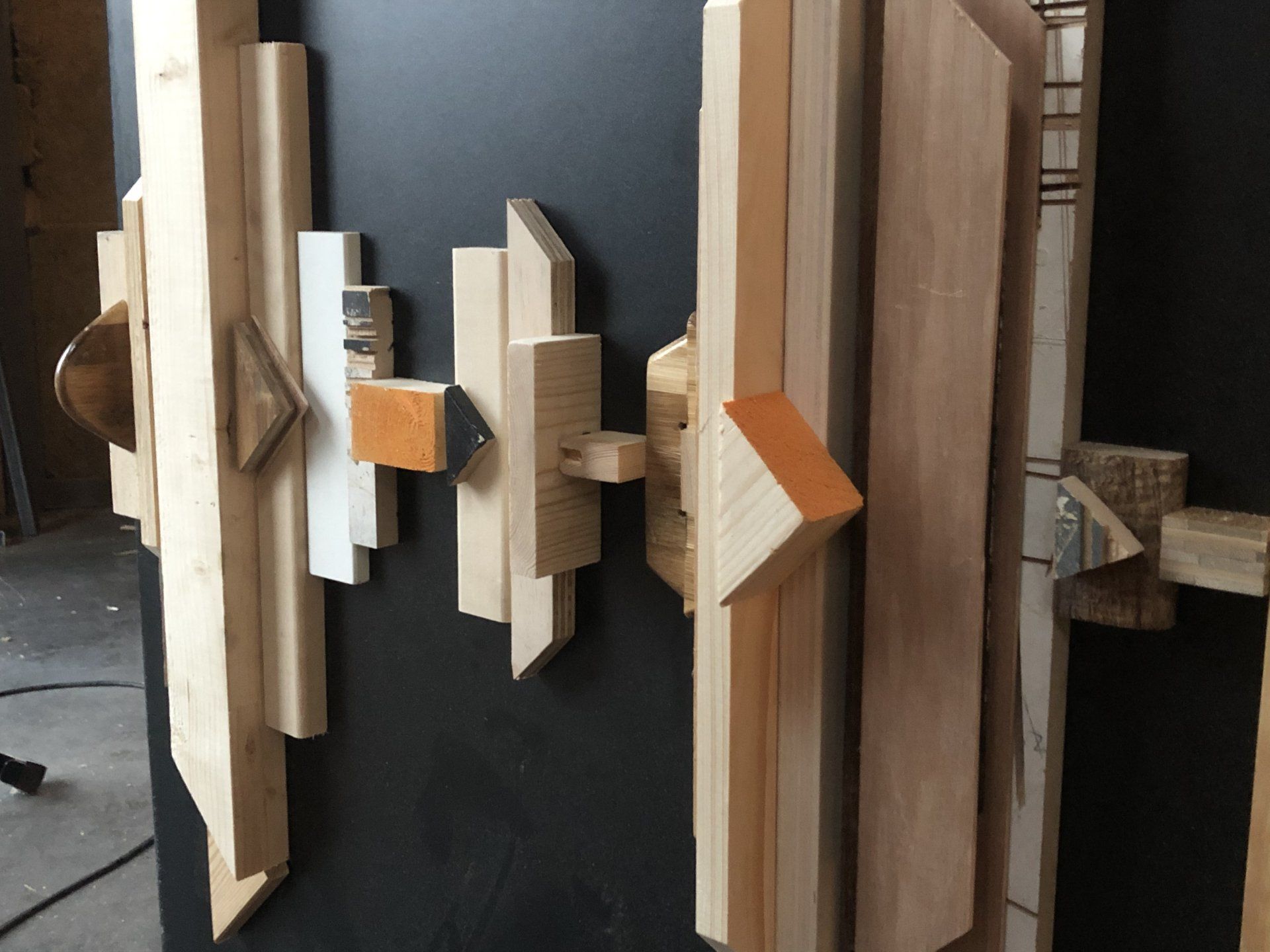 Abstract houten kunstwerk tegen een donkere achtergrond, samengesteld uit geometrische vormen en verschillende houttinten.