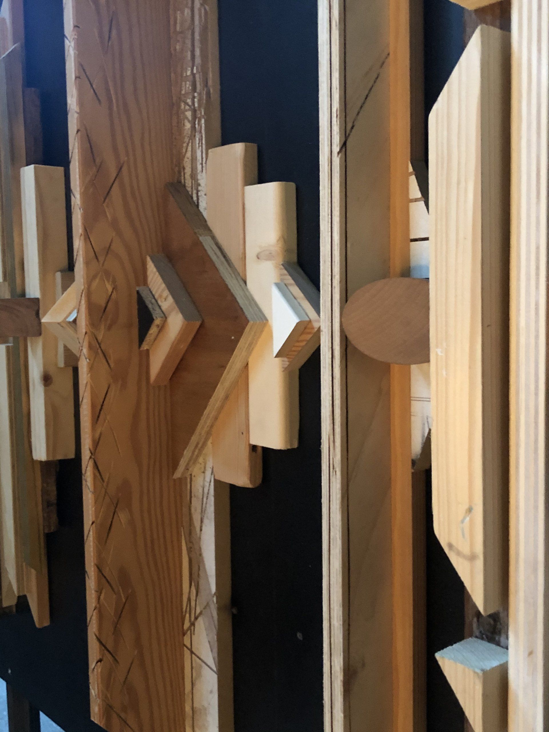 Houten wanddecoratie met geometrische vormen van verschillende groottes, texturen en diepten.