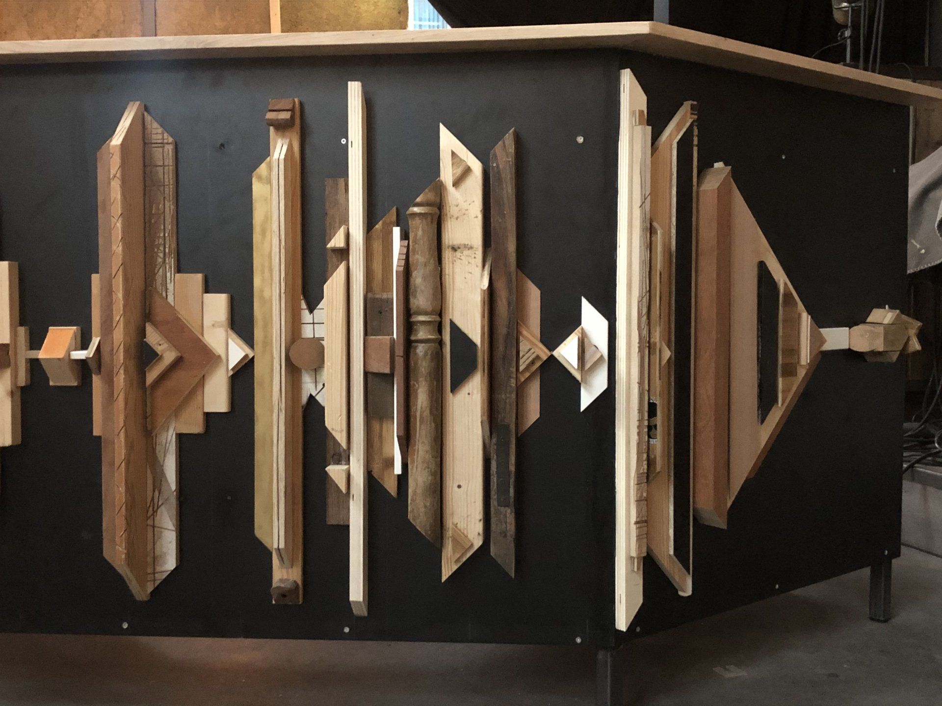 Zwarte kast met geometrische houtkunst, lichte en donkere houtsoorten.
