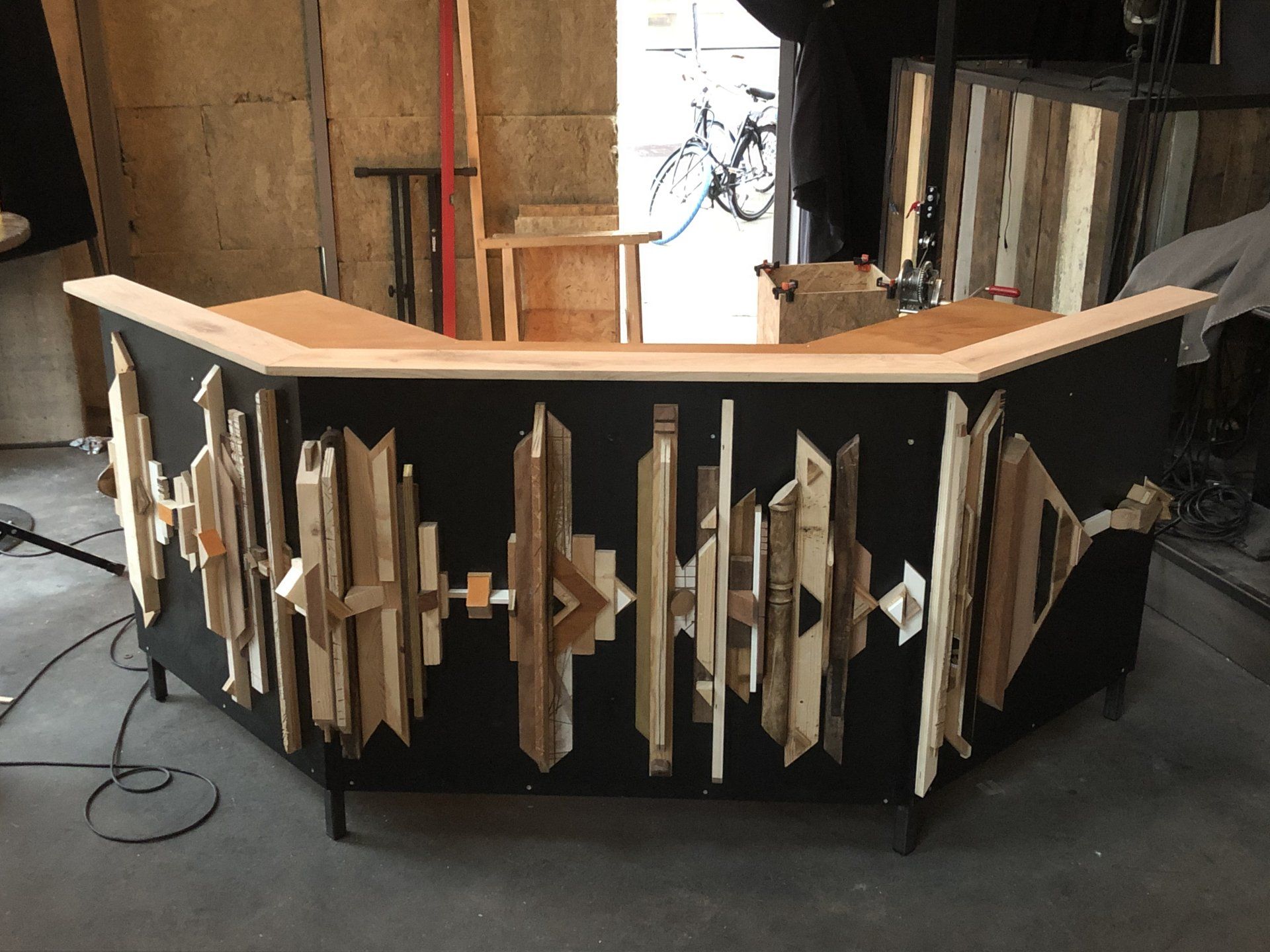 Bar met geometrische houten accenten op zwarte panelen.