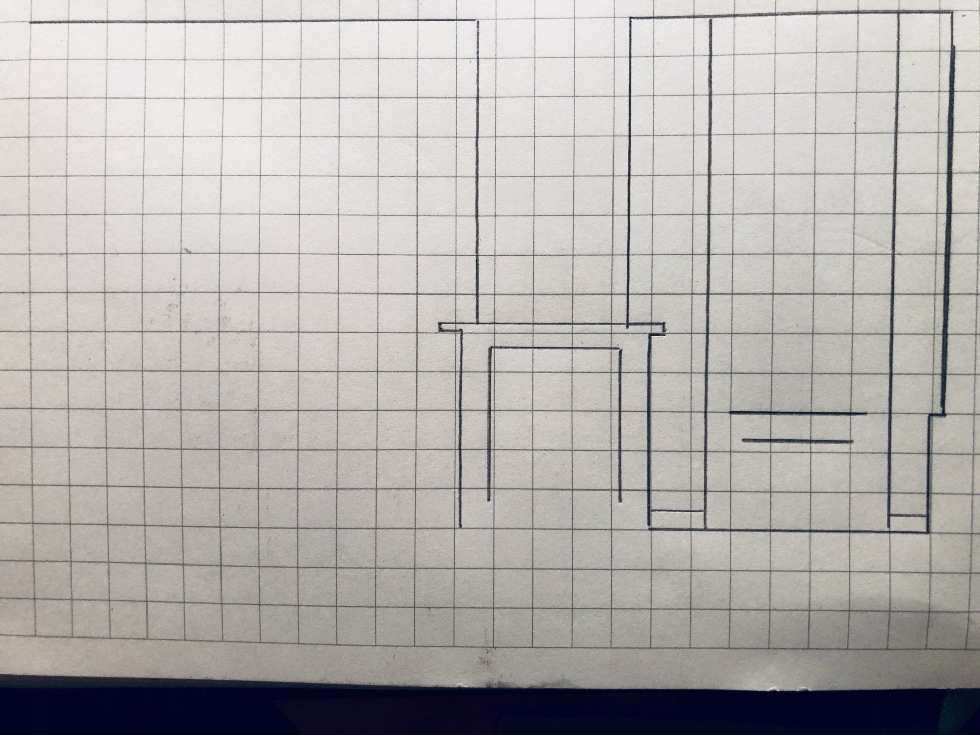 Lijntekening op ruitjespapier: bureau en kast.