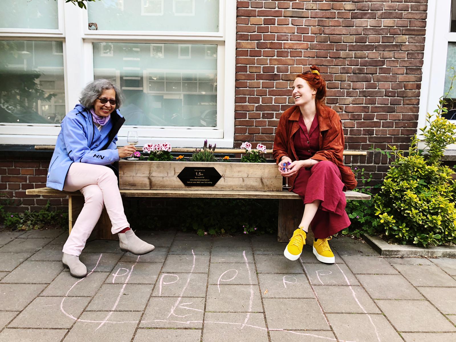 Twee mensen zitten op een bankje voor een bakstenen muur.