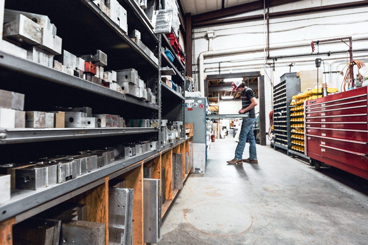 A man is standing in a warehouse with lots of shelves and tools.