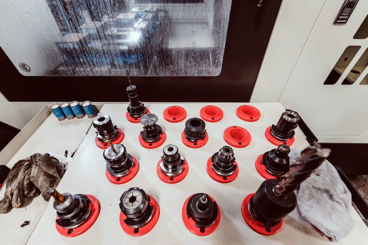 A bunch of drill bits are sitting on a table in front of a machine.
