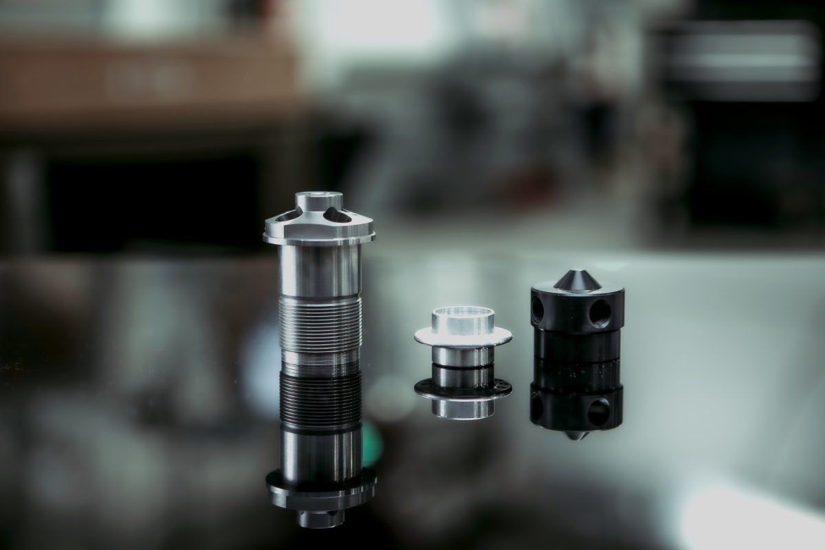 Three metal objects are sitting on top of a glass table.