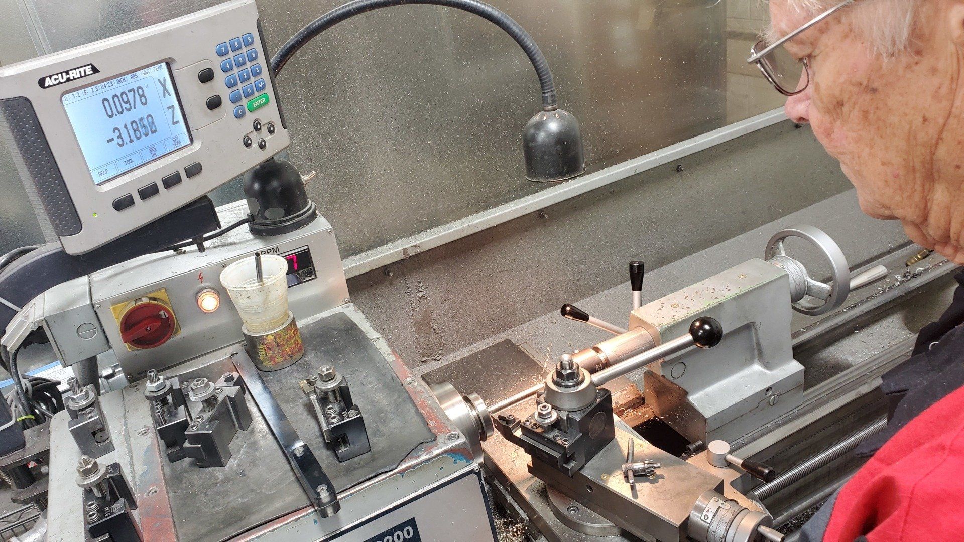 A man is working on a lathe in a factory.
