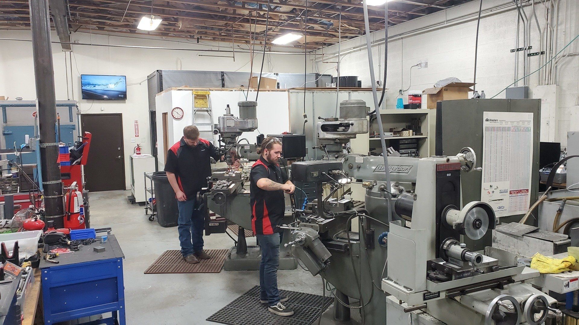 Two men are working on a machine in a factory.