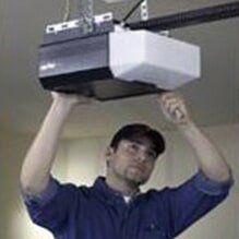 Man in blue shirt adjusting a ceiling-mounted projector with both hands