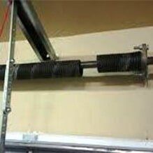 Garage door torsion spring assembly mounted above a door opening.