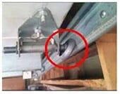 Broken Slide Repair Service — Guaranteed Door Service, Inc. Close-up of metal machinery with a red circle highlighting a silver component under a hinged part.