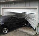 Garage Door Repair — Guaranteed Door Service, Inc. Black car in a garage with a garage door bent and partially collapsing onto it