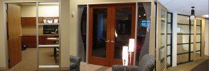 Commercial Interior Door System — Guaranteed Door Service, Inc. Modern interior with wooden sliding doors, glass panels, and a hallway view into a room.
