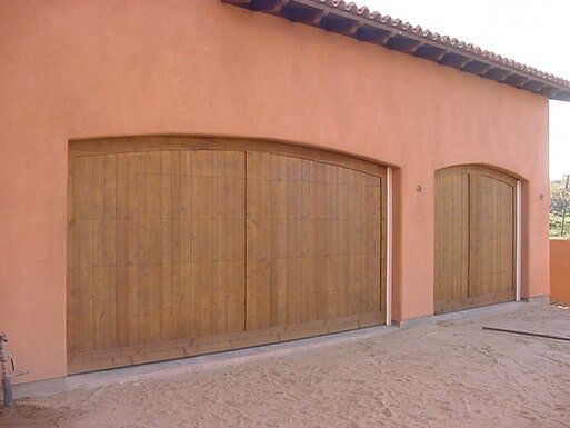 Peach-colored building with large wooden garage doors and a gravel driveway