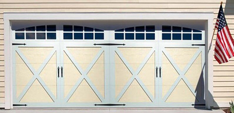 White garage with four beige carriage-style doors and an American flag on the right