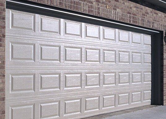 White paneled garage door in a brick exterior wall