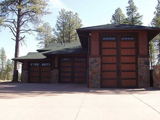 Modern house with three garage doors and a stone exterior, viewed from the driveway