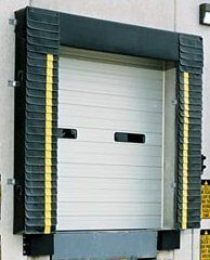 Commercial Garage Doors — Guaranteed Door Service, Inc. Industrial loading dock door with black and yellow bumpers and a white roll-up shutter