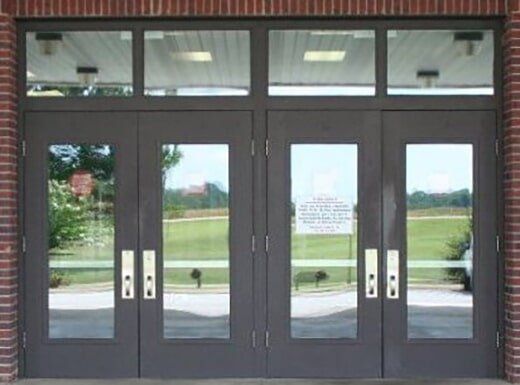 Glass double doors with dark frames and metal handles on a brick building entrance