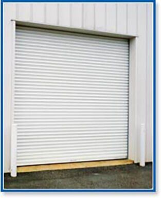 Closed white roll-up garage door on a beige industrial building.