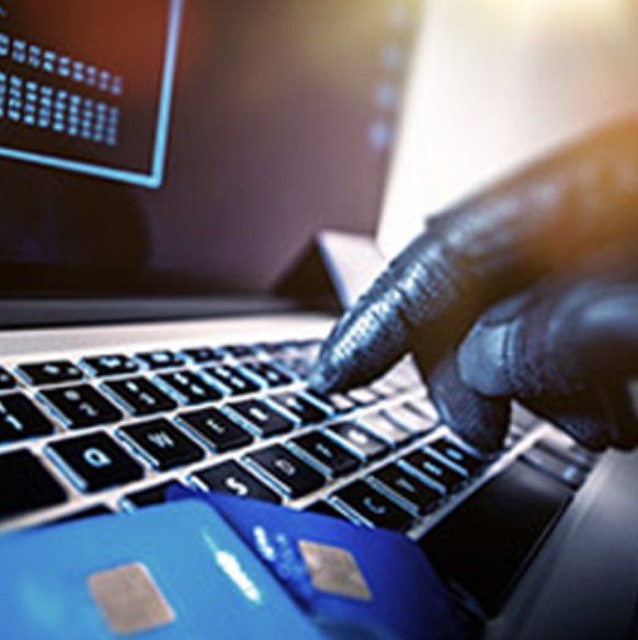 A person is using a laptop with a credit card on the keyboard.