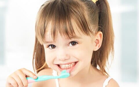 Oral Exams — Kid Smiling While Brushing Her Teeth in Erie, PA Oral Exams — Kid Smiling While Brushing Her Teeth in Erie, PA