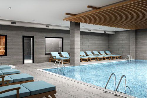 there is a large indoor swimming pool with chairs around it .