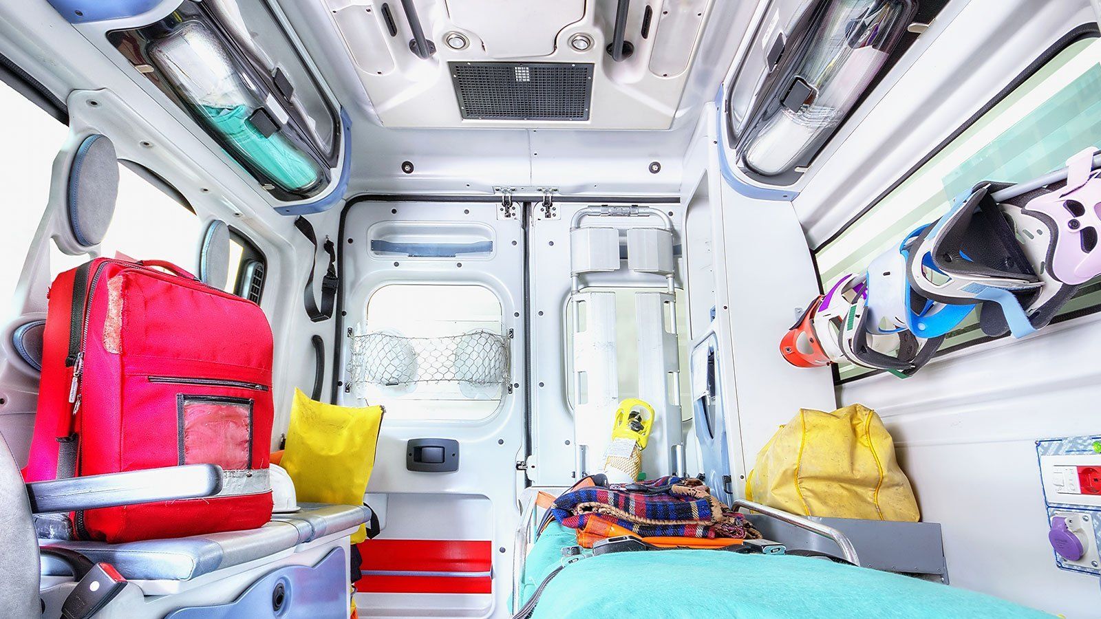 All'interno di un'ambulanza ben illuminata, attrezzature e forniture mediche di emergenza, letto vuoto.