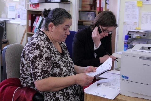 A lady in a black suit, using a pen to demonstrate a point to another lady