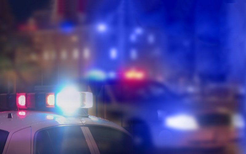 Police cars with flashing red and blue lights at night.
