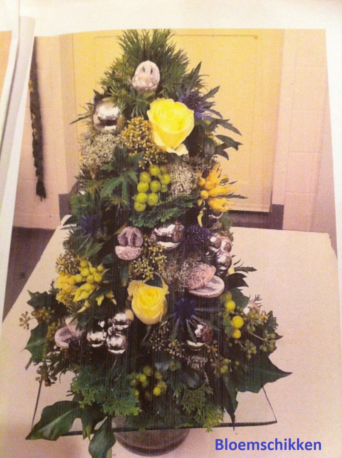 Floral Christmas tree arrangement with yellow roses, silver ornaments, and green foliage.