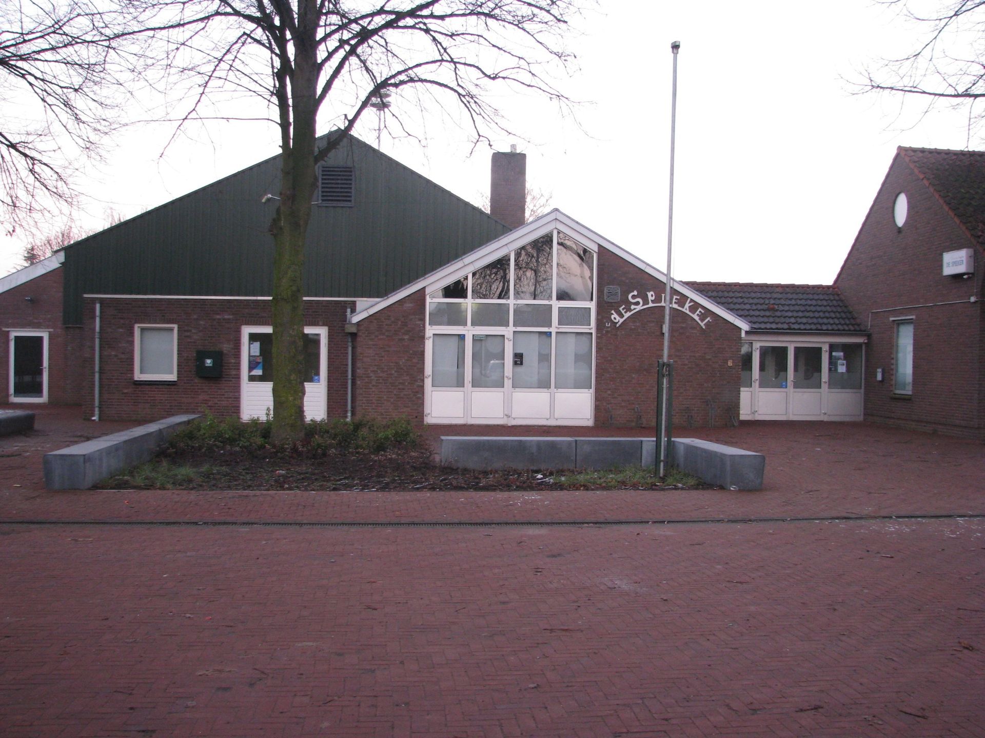 Red brick building with green roof, white doors and windows. 
