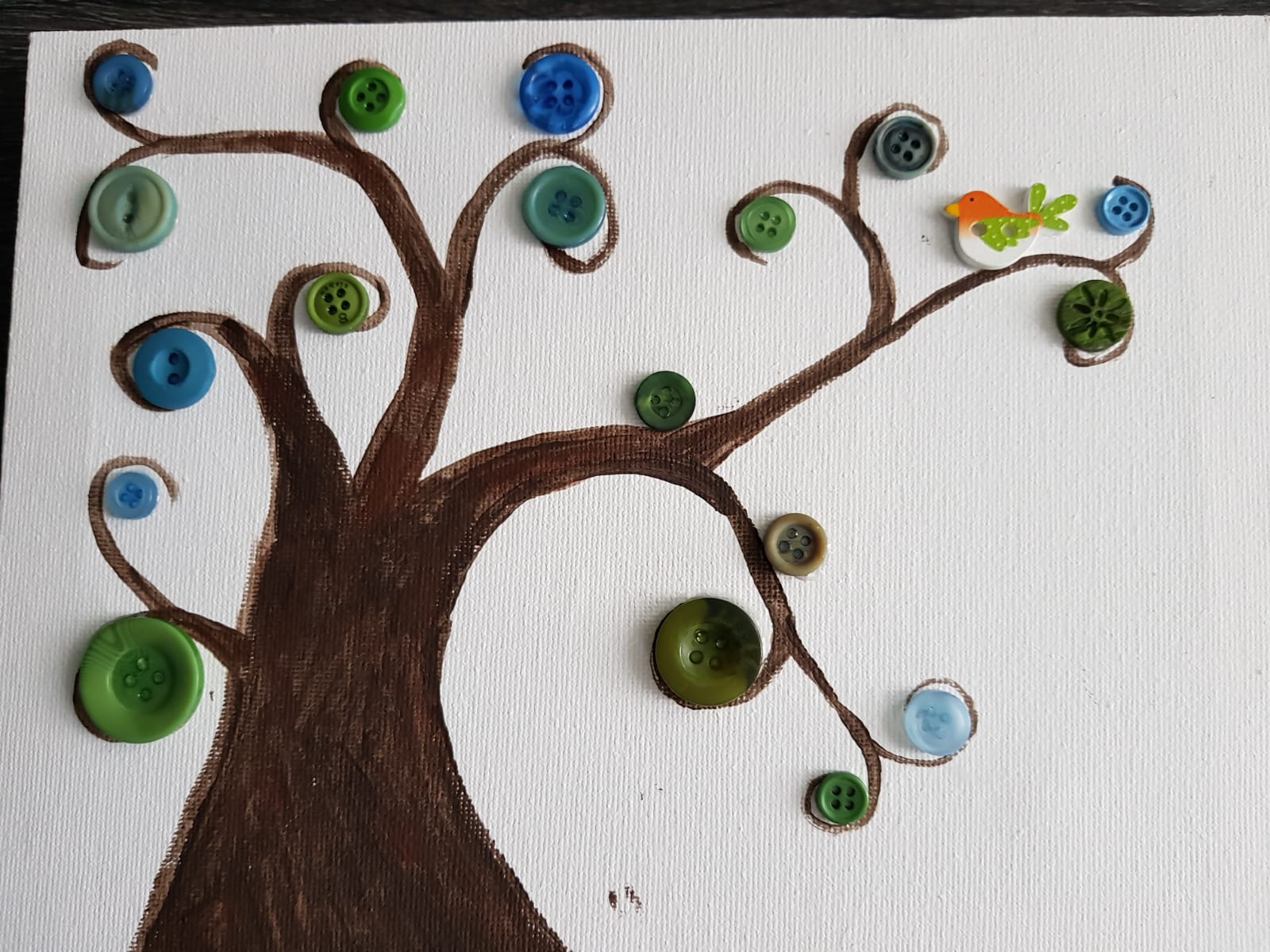 Button tree art with brown trunk and green and blue buttons. A bird sits on a branch.