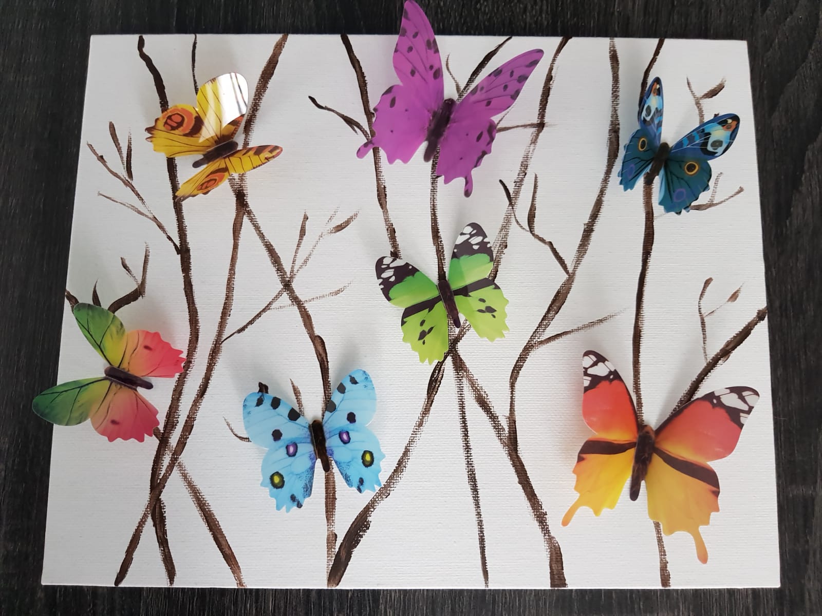 Butterflies of various colors on a white canvas with painted brown branches.