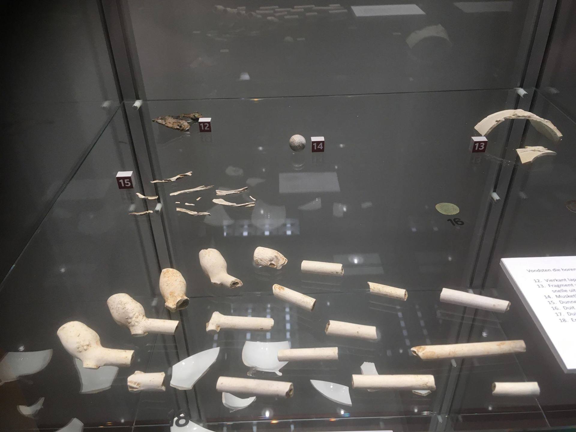 Display case with historical artifacts, including pipe fragments and other small items.