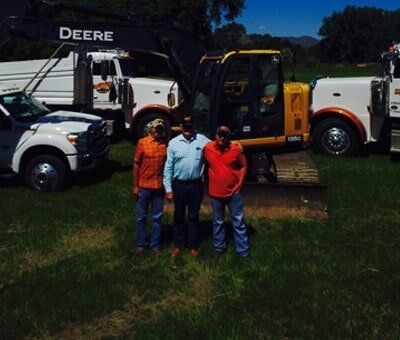 Three People with Trucks Behind — Excavation in Laporte, CO Three People with Trucks Behind — Excavation in Laporte, CO