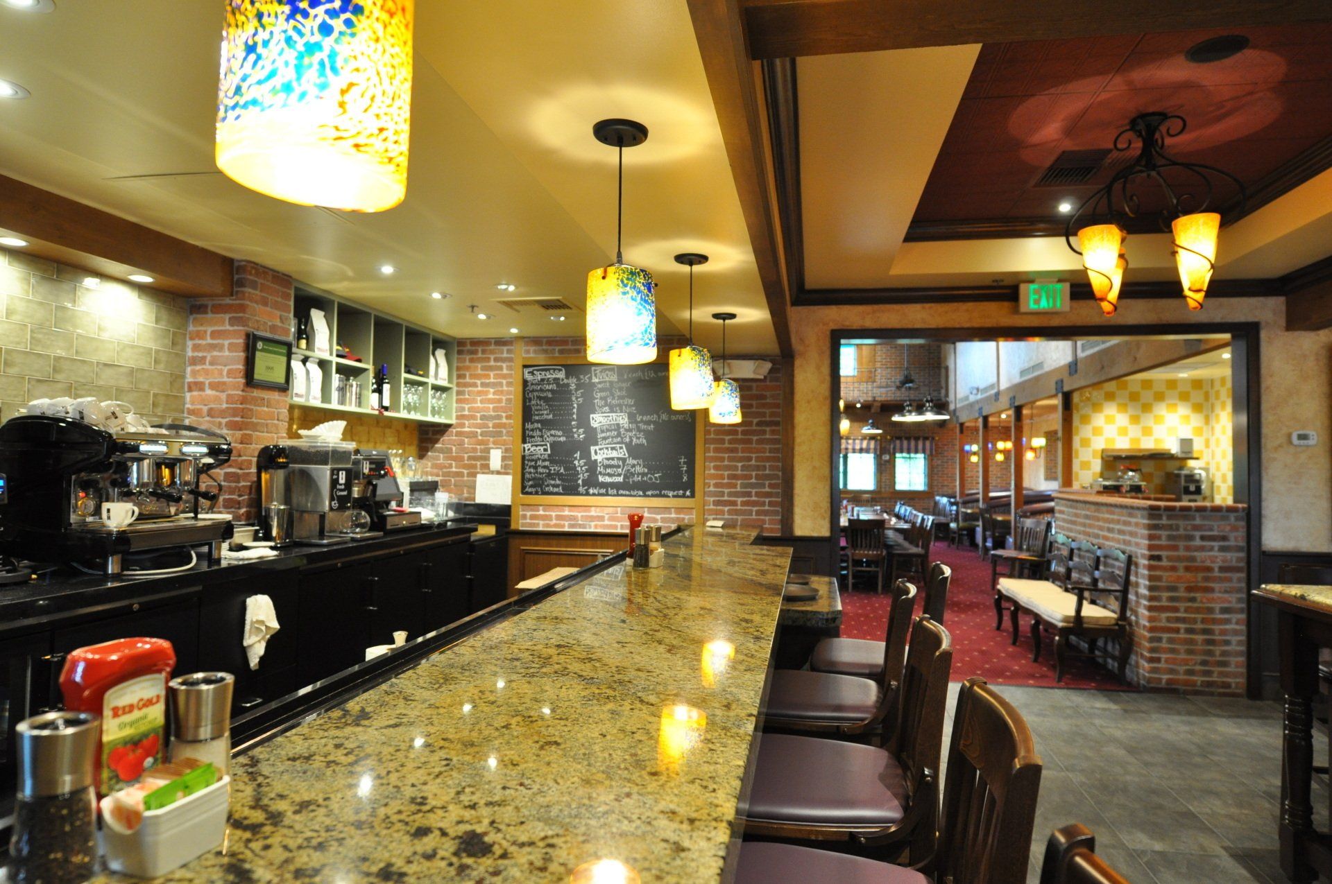 A long bar in a restaurant with a chalkboard on the wall