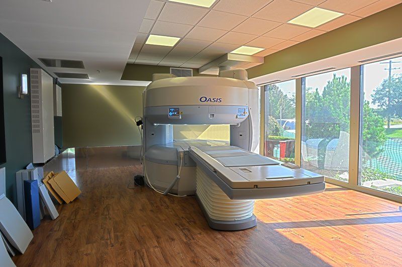 A large mri machine is sitting in a room with lots of windows.