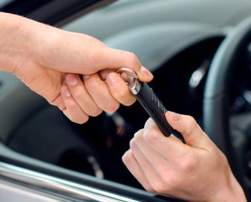 Eine Person gibt einer anderen Person einen Autoschlüssel