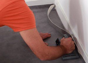man using a tool to lay carpet