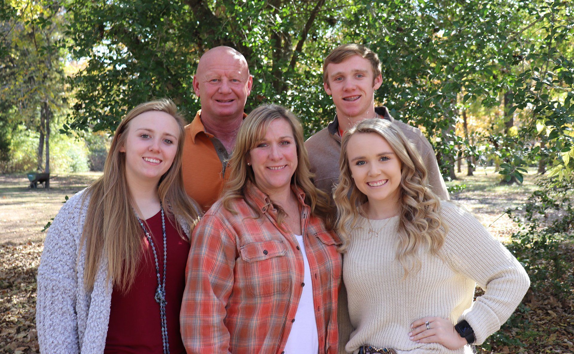 A family is posing for a picture in a park.