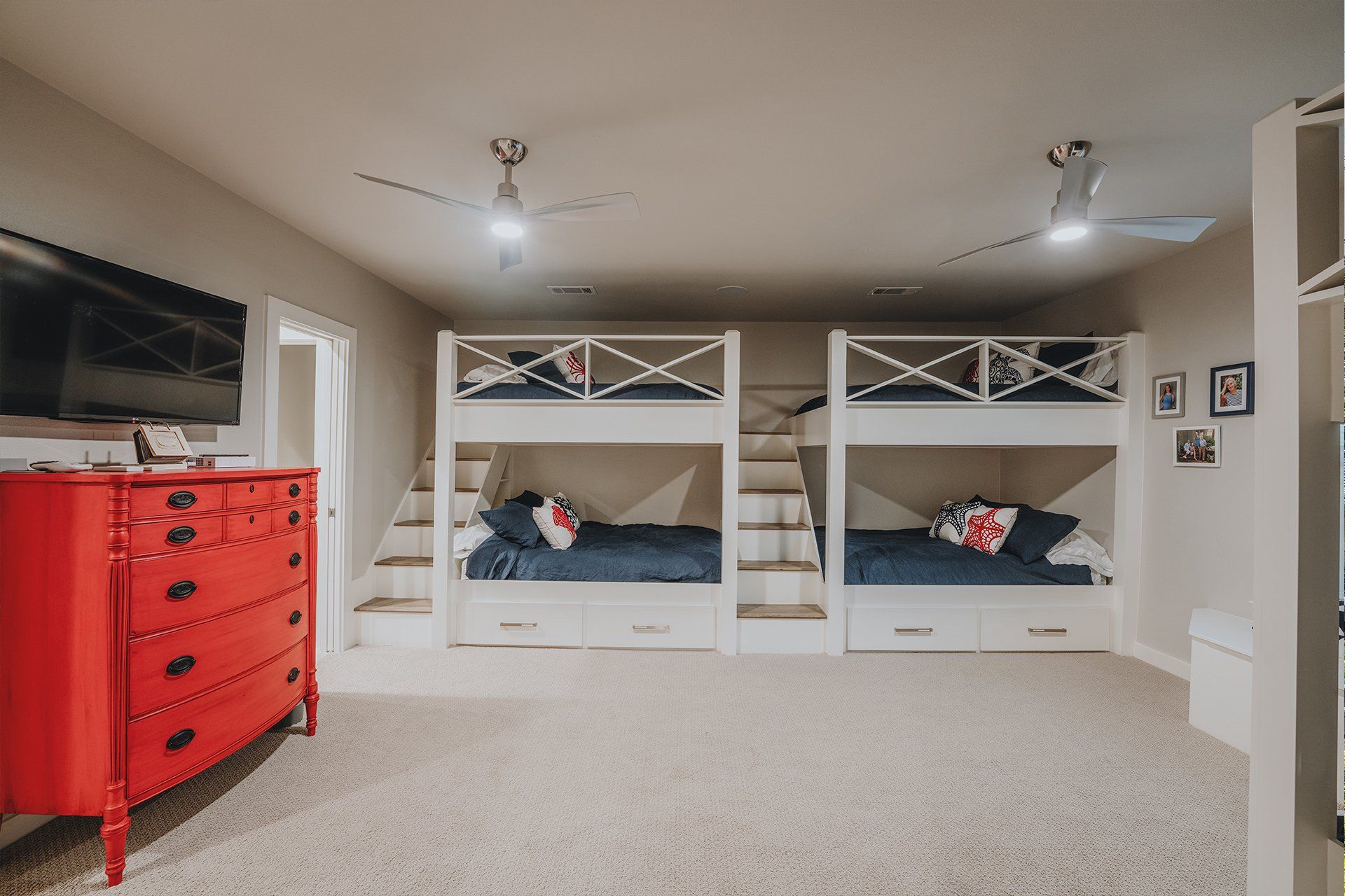 A bedroom with three bunk beds and a red dresser.