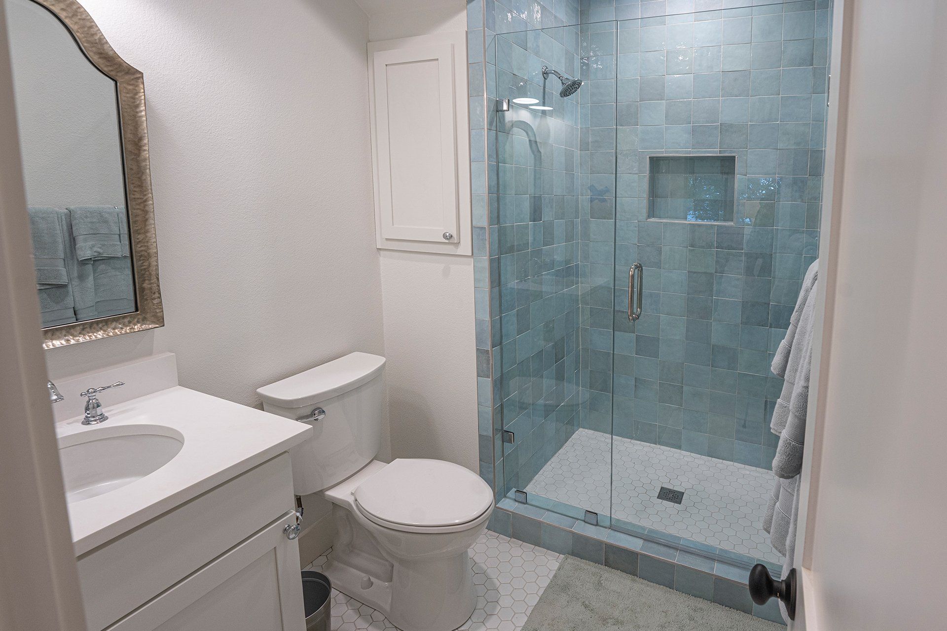 A bathroom with a toilet , sink , mirror and walk in shower.