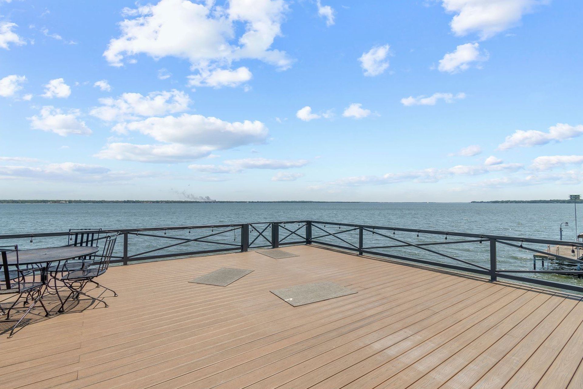 A wooden deck overlooking a body of water with a table and chairs.
