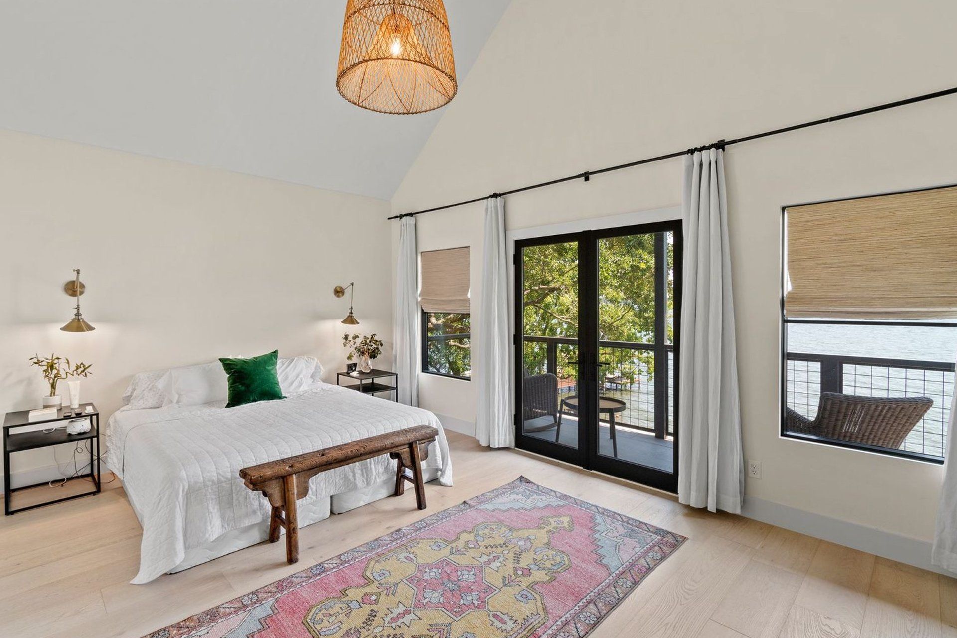 A bedroom with a large bed , bench , rug and sliding glass doors.