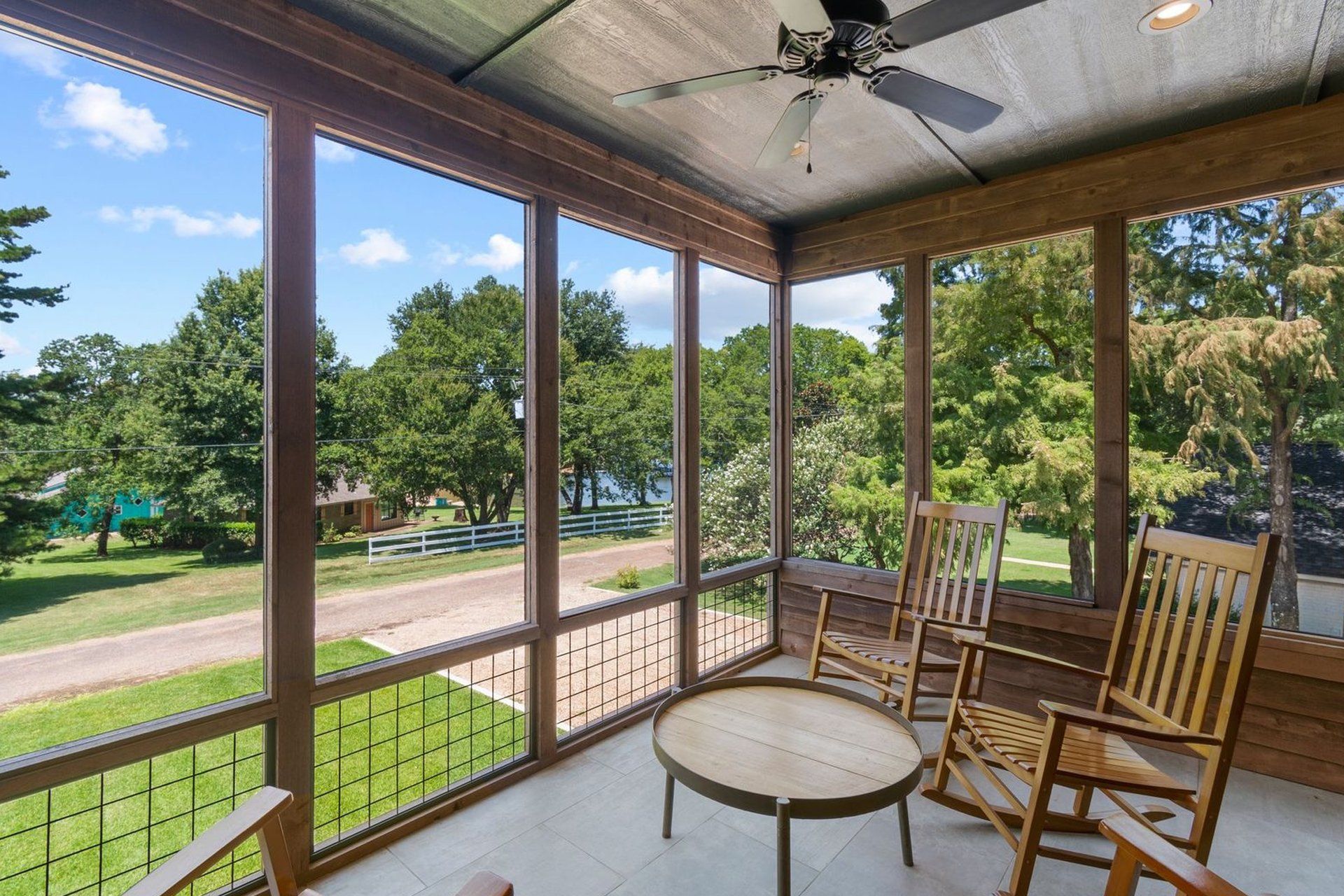 A screened in porch with rocking chairs and a table