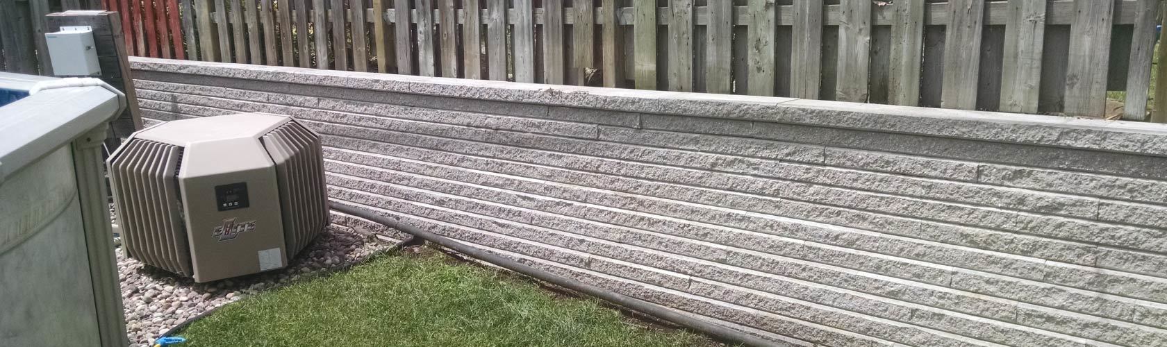 grey unistone wall and fence next to grass